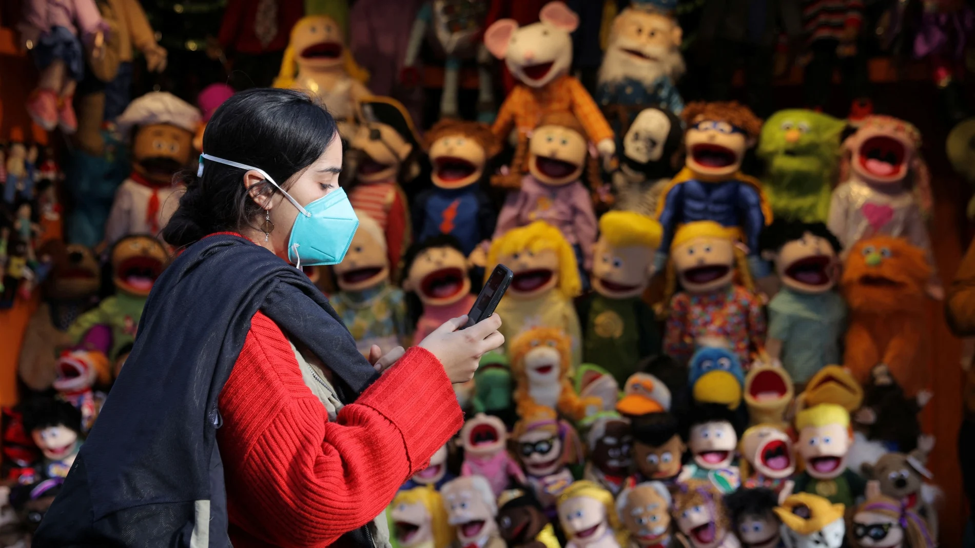 Una mujer camina con mascarilla por Manhattan por delante de una tienda de marionetas