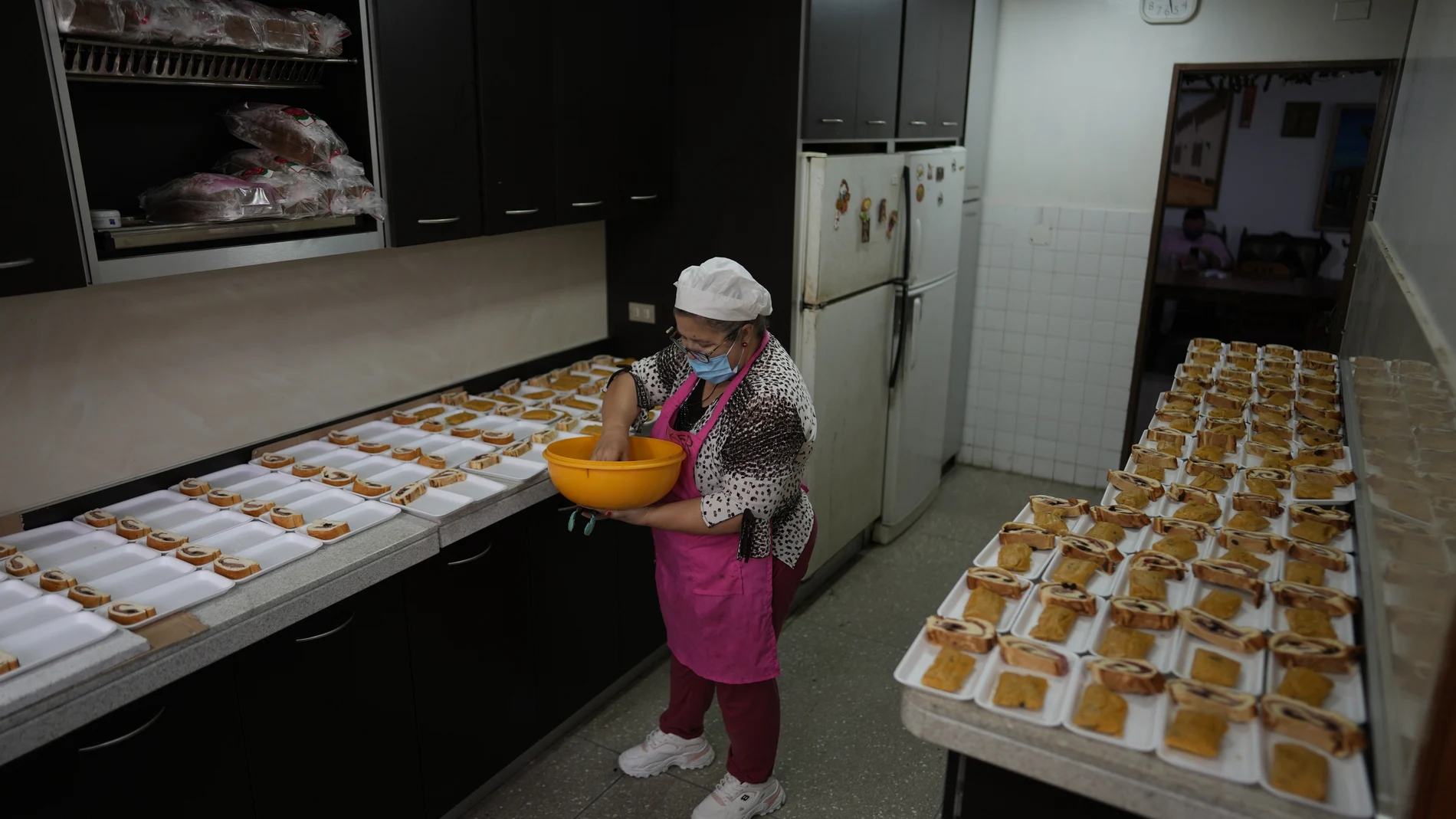 A woman prepares Christmas meals to be served at the San Miguel Archangel church as a part of Christmas celebrations in Caracas, Venezuela, Tuesday, Dec. 21, 2021.The church serves a traditional Venezuela Christmas meal for about two hundred children including nursing mothers. (AP Photo/Ariana Cubillos)
