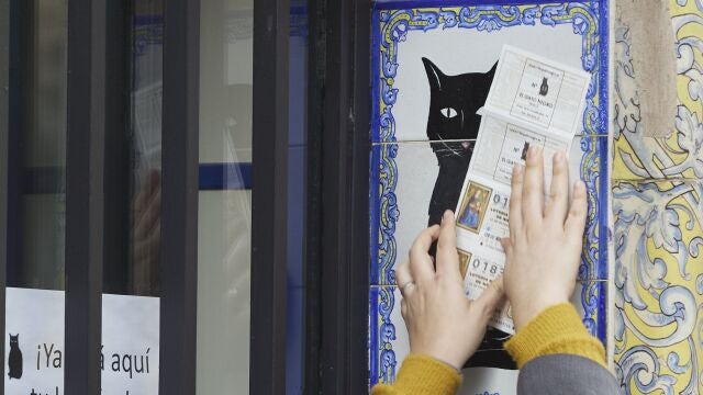 Una persona frota un billete de Lotería de Navidad por el azulejo de la Administración de Lotería el Gato Negro de Sevilla. Joaquín Corchero / Europa Press