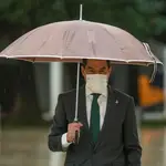 El presidente de la Junta, Juanma Moreno, se protege de la lluvia con un paraguas tras la sesión de control al ejecutivo. EFE/ Raúl Caro