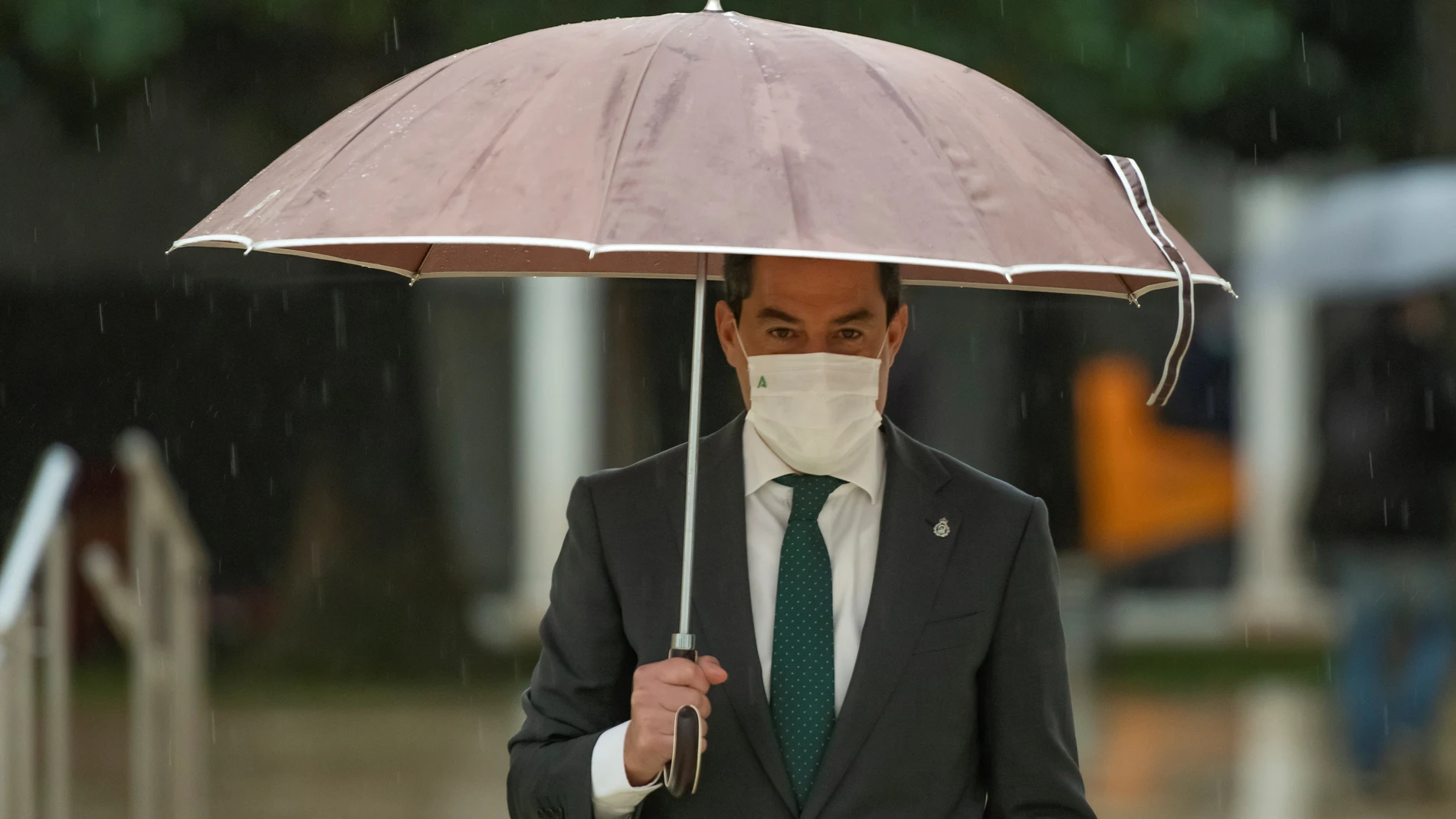 El presidente de la Junta, Juanma Moreno, se protege de la lluvia con un paraguas tras la sesión de control al ejecutivo. EFE/ Raúl Caro