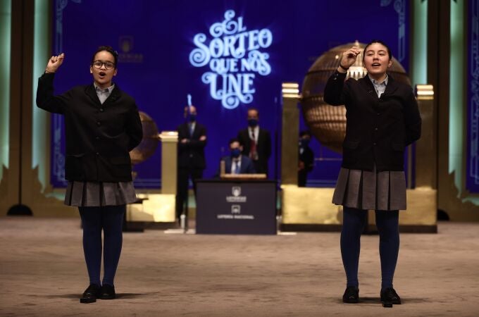 Paula Figuereo (i) y Yanisse Alexandra, dos de las niñas de la residencia de San Ildefonso, posan minutos después de cantar el primer premio 86.148, durante la celebración del Sorteo Extraordinario de la Lotería de Navidad 2021 en el Teatro Real de Madrid, a 22 de diciembre de 2021, en Madrid, (España). A diferencia del año pasado en el que la evolución de la pandemia hizo imposible la presencia de público, el sorteo de 2021 se celebra con aforo reducido de público. En esta edición se repartirán un total de 2.408 millones de euros en premios, la misma cantidad que en 2020. Entre los premios repartidos por la Lotería de Navidad destaca el popularmente conocido como 'Gordo' de Navidad, el primer premio, de 400.000 euros al décimo. 22 DICIEMBRE 2021;NAVIDAD;LOTERIA;TEATRO REAL;MADRID Eduardo Parra / Europa Press 22/12/2021