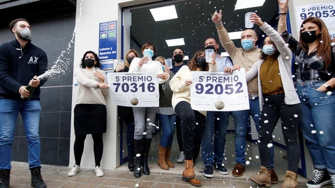 Trabajadores y vecinos de la administración número 3 de Manises, sita en la calle Maestro Guilen, celebran la venta de dos de los quintos premios, el número 92.052 y el 70.316