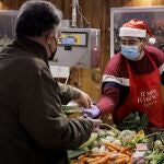 Un tendero con gorro de Papá Noel atiende a un cliente en el Mercado Central de València