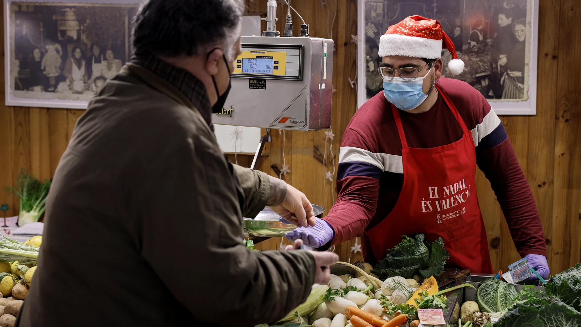 Un tendero con gorro de Papá Noel atiende a un cliente en el Mercado Central de València