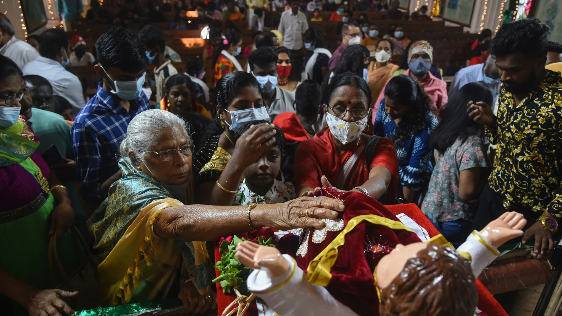 Feligreses cristianos indios tocan una figura del Niño Jesús durante la misa del día de Navidad en la basílica catedral de Santhome (santo Tomás)en Chennai, en la India, este sábado, 25 de diciembre