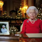 In this undated photo issued on Thursday Dec. 23, 2021, Britain&#39;s Queen Elizabeth II records her annual Christmas broadcast in Windsor Castle, Windsor, England. The photograph at left shows The Queen and Prince Philip taken in 2007 at Broadlands to mark their Diamond wedding anniversary. (Victoria Jones/Pool via AP)