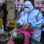 Un sanitario hace una prueba covid a una mujer en Jammu, la India
