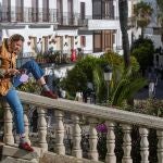 Una joven disfruta del buen tiempo apoyada en una baranda de la Plaza España de Vejer de la Frontera (Cádiz)