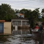 Luzia Barbosa de Oliveira, not pictured, accompanied by family members, is transported on a boat to her home partially submerged by flood waters in Sambaituba, a rural area of Ilheus, Bahia state, Brazil, Dec. 29, 2021. Over 100 cities in the northeastern Brazilian state of Bahia are in a state of emergency because of flooding due to heavy rains that have been pounding the region since the end of November. (AP Photo/Raphael Muller)