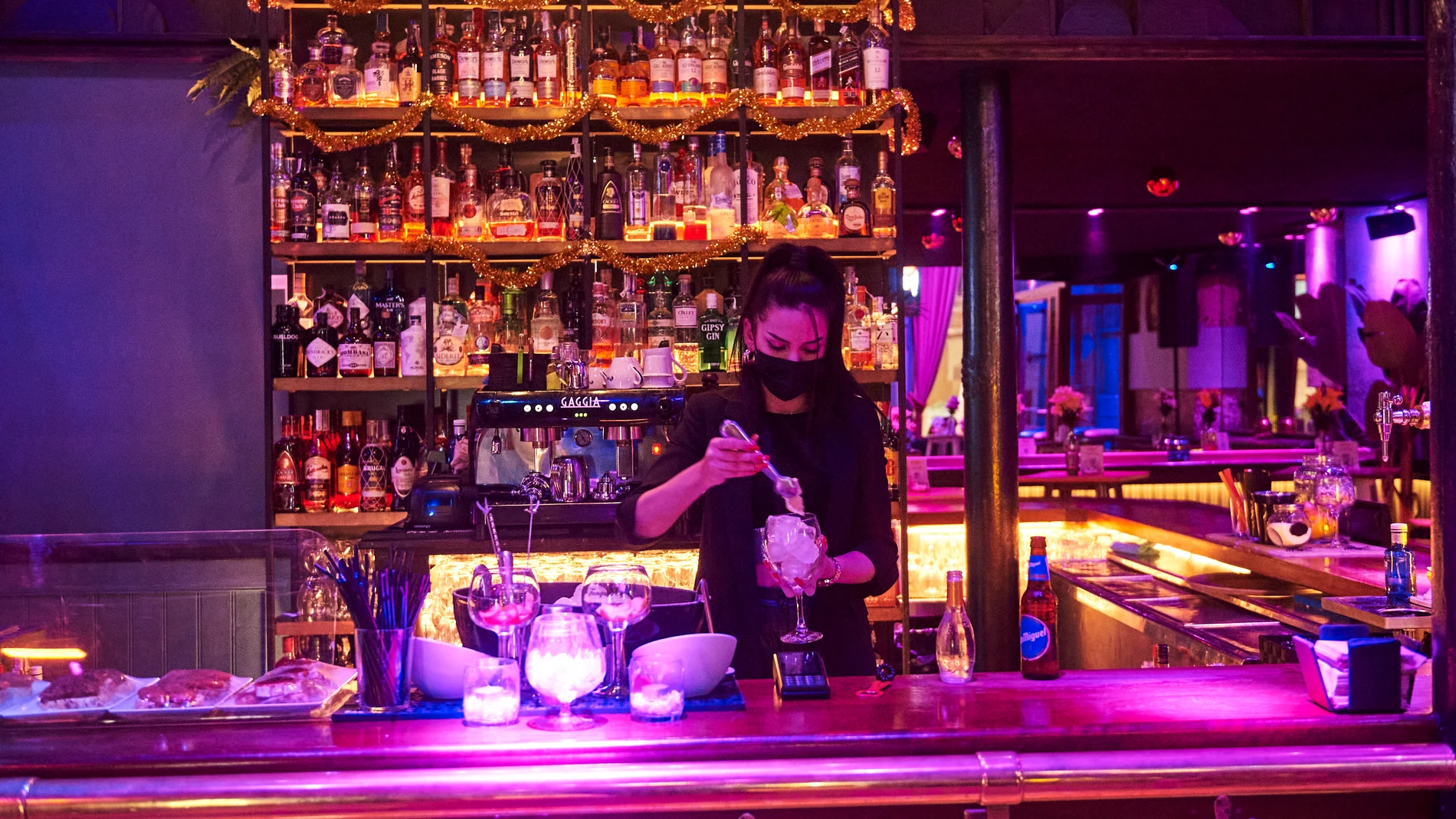 Una trabajadora prepara copas en la barra de un bar