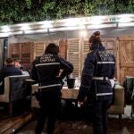 Dos agentes comprueban el código QR del certificado de vacunación de los clientes de un bar en Roma