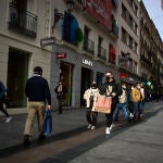 Varias personas con bolsas pasean en una calle comercial del centro de Madrid