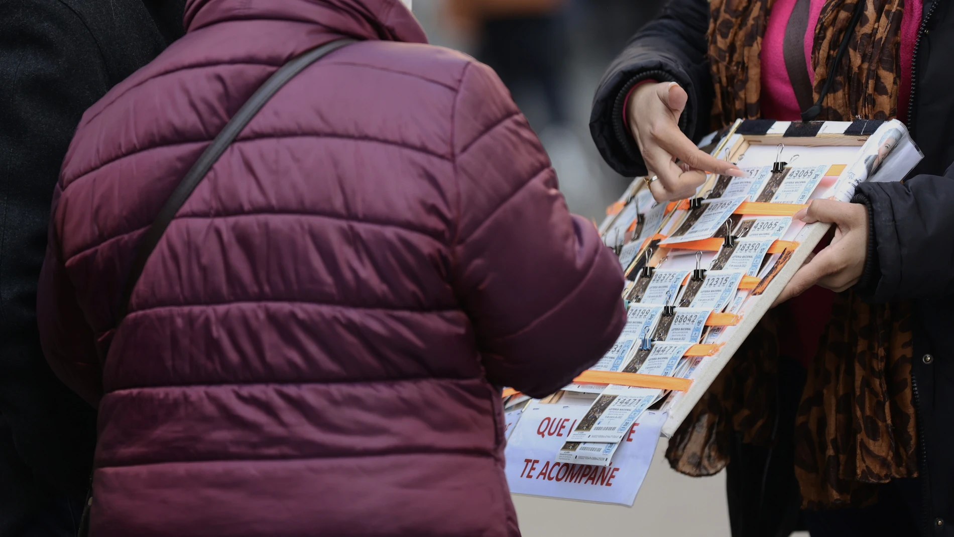 Una mujer compra un décimo de lotería a una vendedora ambulante, tres días antes del Sorteo de La Lotería del Niño, a 3 de enero de 2022, en Madrid, (España)