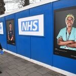 Un hombre pasea junto a un dispositivo sanitario de admisiones construido en el aparcamiento del Hospital St. George, en el sur de Londres