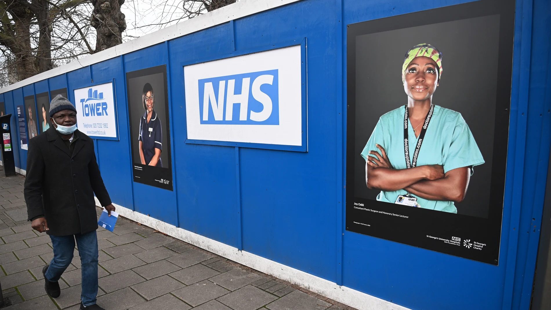 Un hombre pasea junto a un dispositivo sanitario de admisiones construido en el aparcamiento del Hospital St. George, en el sur de Londres