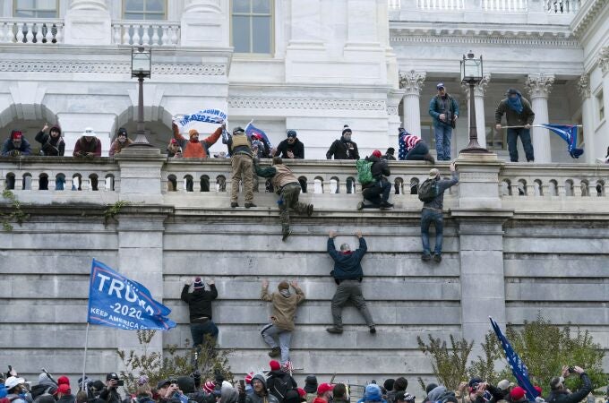 Insurrectos violentos leales al entonces presidente Donald Trump escalan el muro oeste del Capitolio de Estados Unidos en Washington, el 6 de enero de 2021