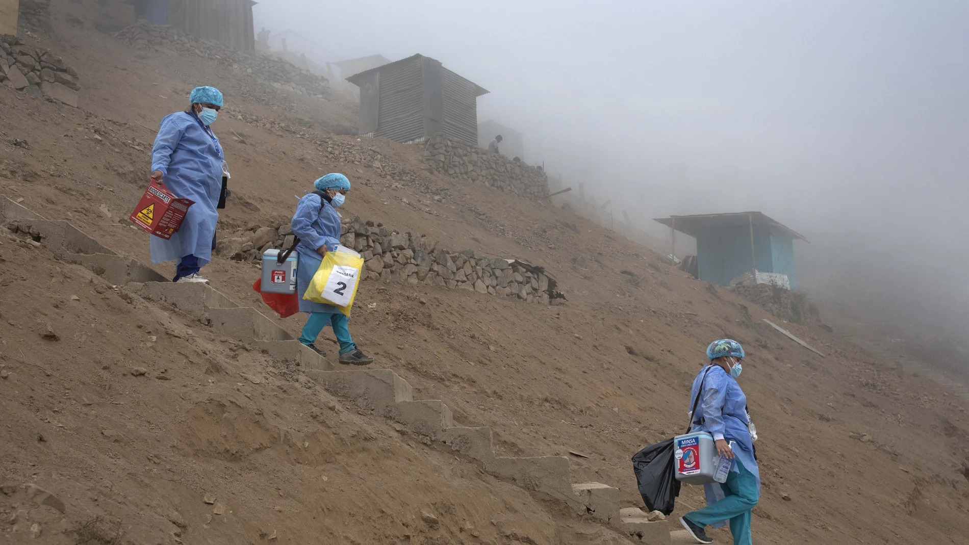 FILE - Healthcare workers carry coolers filled with doses of the Pfizer COVID-19 vaccine during a door-to-door vaccination campaign in the Villa Maria del Triunfo district on the outskirts of Lima, Peru, Nov. 16, 2021. Peru confirmed on Tuesday, Jan. 4, 2022, the start of a third wave of new coronavirus infections. (AP Photo/Guadalupe Pardo, File)