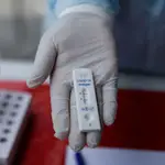 Un trabajador de sanidad sostiene una prueba de antígenos positiva en coronavirus