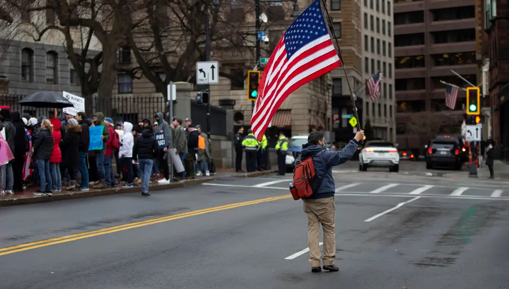 Un manifestante que porta una bandera de EE.UU. se une a otros que piden el fin de los mandatos de vacunación implementados por los políticos locales
