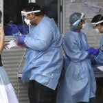Health workers attend at a COVID-19 testing site in Brisbane, Australia Friday, Jan. 7, 2022. Australiaâ€™s most populous state reinstated some restrictions and suspended elective surgeries on Friday as COVID-19 cases surged to another new record. (Jono Searle/AAP Image via AP)