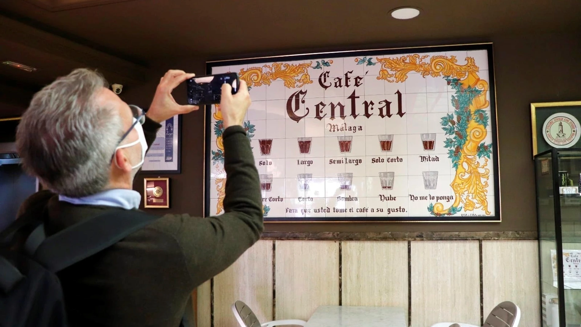 Un turista fotografía el emblemático cartel de Café Central, histórico bar que inventó unos peculiares nombres para pedir esta cotidiana y popular bebida en sus diversas formas. EFE/Daniel Luque