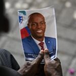 FILE - A person holds a photo of late Haitian President Jovenel Moise during his memorial ceremony at the National Pantheon Museum in Port-au-Prince, Haiti, Tuesday, July 20, 2021. Authorities in the Dominican Republic said Monday, Jan. 10, 2022, that they have arrested a key suspect in the killing of President Moise with help from the U.S. (AP Photo/Matias Delacroix, File)