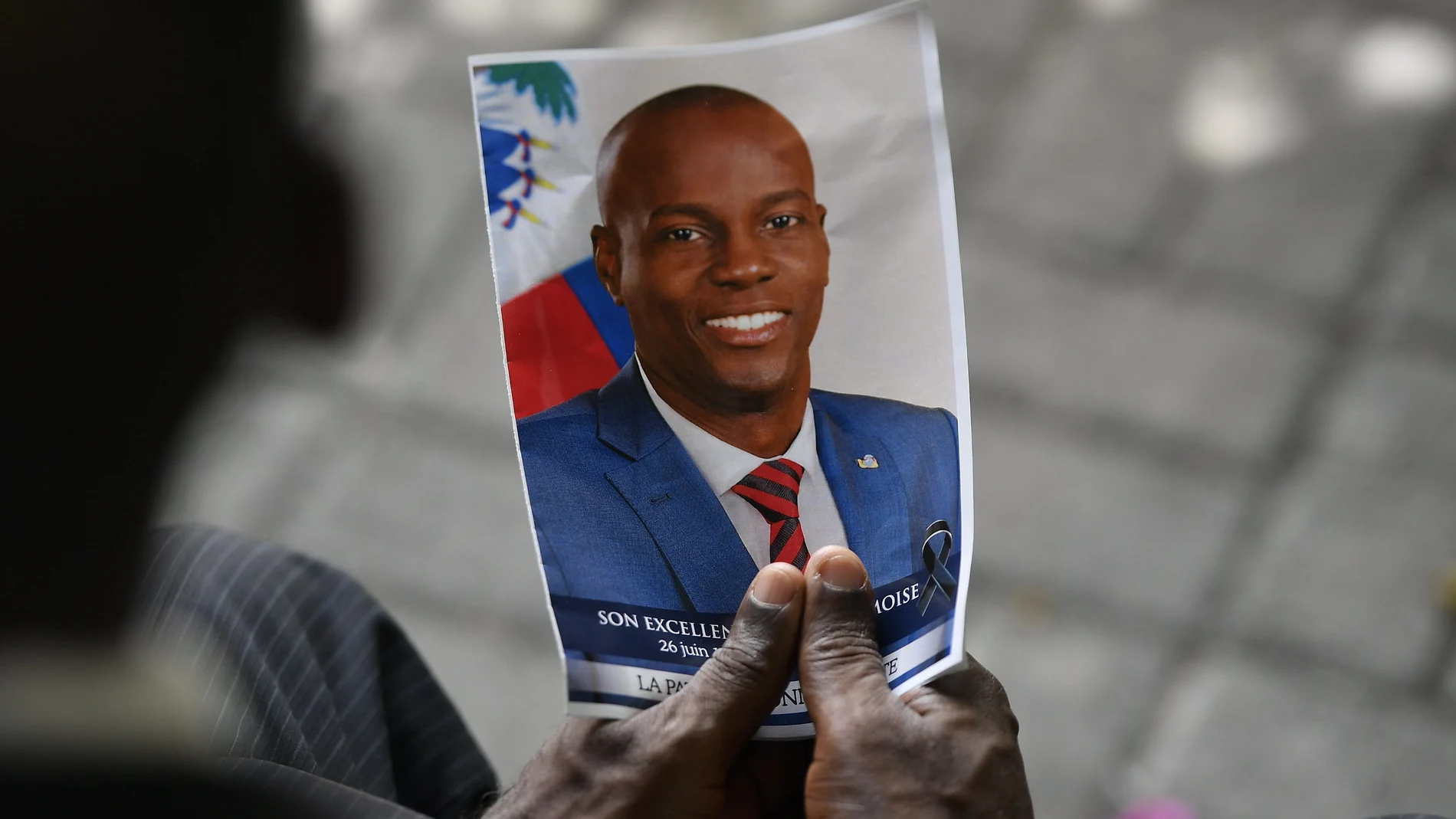 FILE - A person holds a photo of late Haitian President Jovenel Moise during his memorial ceremony at the National Pantheon Museum in Port-au-Prince, Haiti, Tuesday, July 20, 2021. Authorities in the Dominican Republic said Monday, Jan. 10, 2022, that they have arrested a key suspect in the killing of President Moise with help from the U.S. (AP Photo/Matias Delacroix, File)