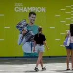 Dos aficionadas pasan por delante de una imagen de Djokovic en el Melbourne Park