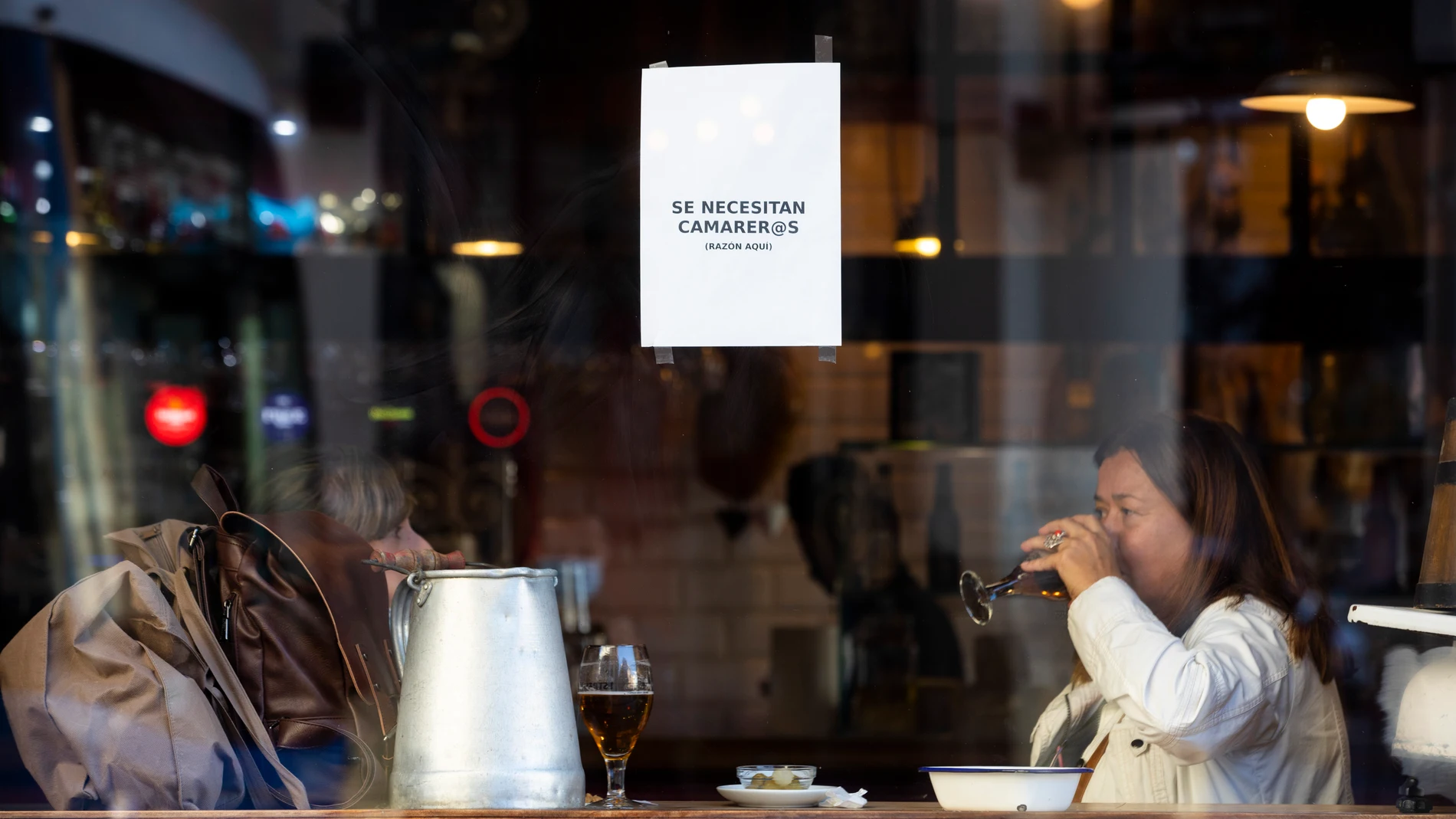 Imagen del escaparte de un bar en el que cuelga un cartel que reza "Se necesitan camareros".
