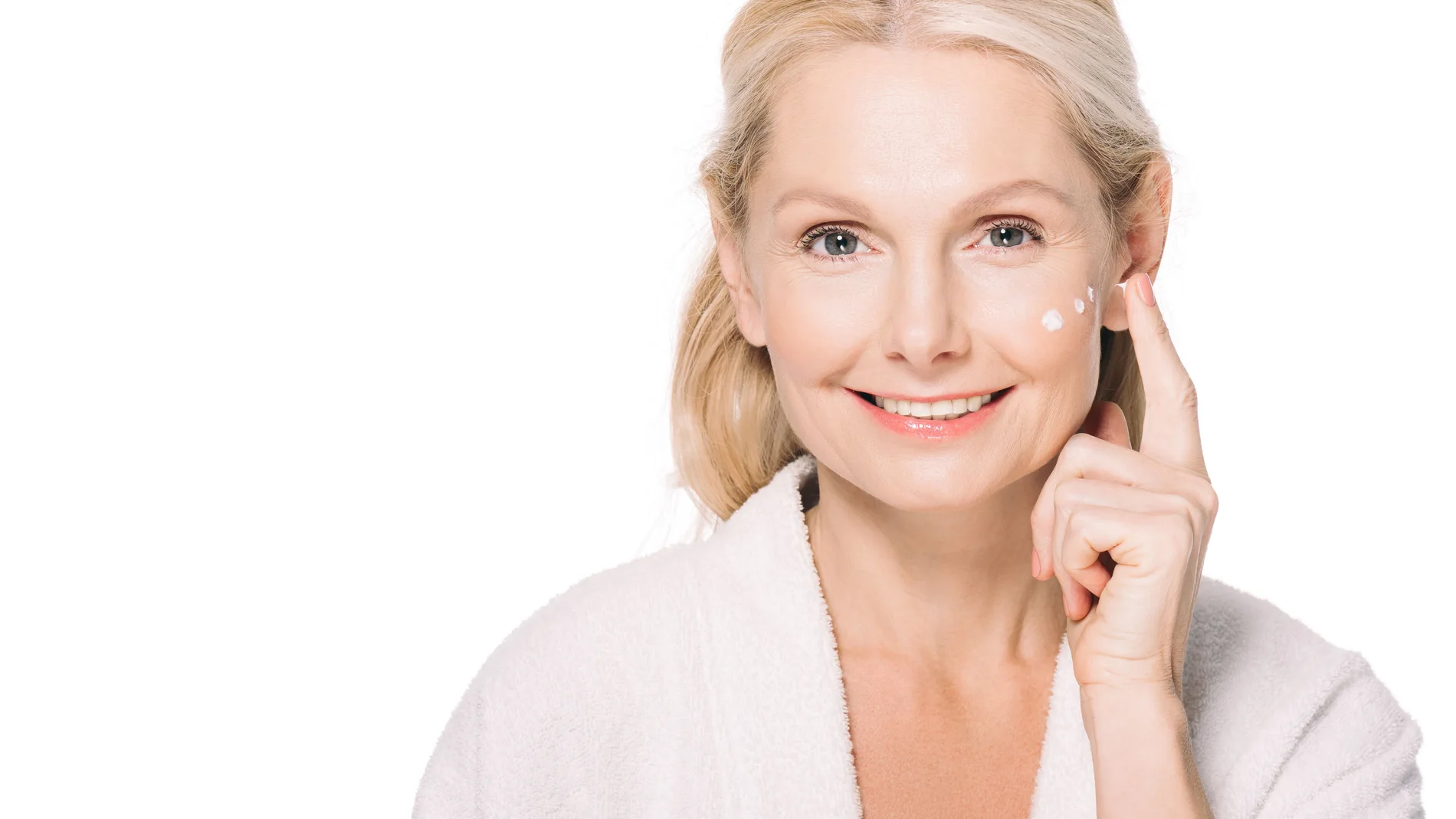 Happy mature woman applying cosmetic cream