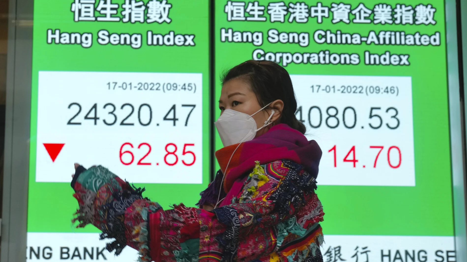 Una mujer pasa por delante de un panel con los indicadores de la bolsa china