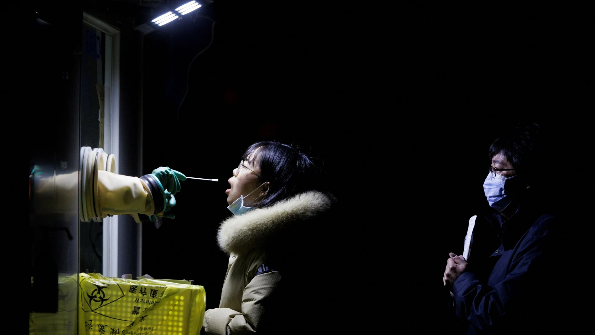 A woman receives a throat swab test at a street booth as the coronavirus disease (COVID-19) pandemic continues in Beijing, China, January 17, 2022. REUTERS/Thomas Peter