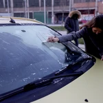Un mujer retira el hielo de su coche tras la fuerte helada caída esta madrugada en el interior de España