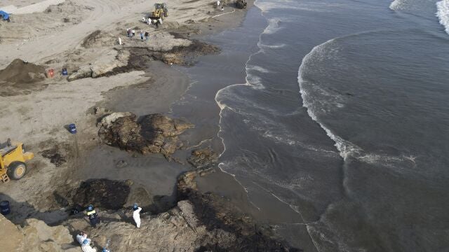 Workers clean up an oil spill at Cavero beach in Ventanilla, Callao, Peru, Monday, Jan. 17, 2022. Unusual high waves that authorities attribute to the eruption of the undersea volcano in Tonga caused the spill on the Peruvian Pacific coast as a ship was loading oil into La Pampilla refinery on Sunday. (AP Photo/Martin Mejia8