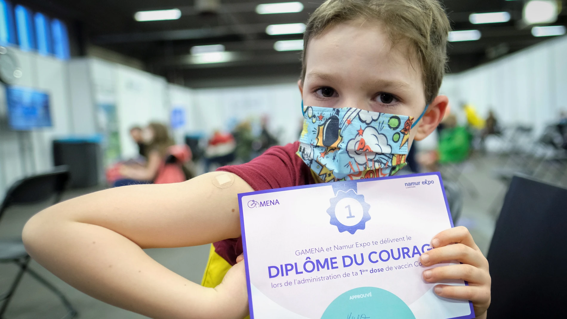 Hugo, de seis años, posa con su certificado de vacunación en la Expo de Namur, en Bélgica