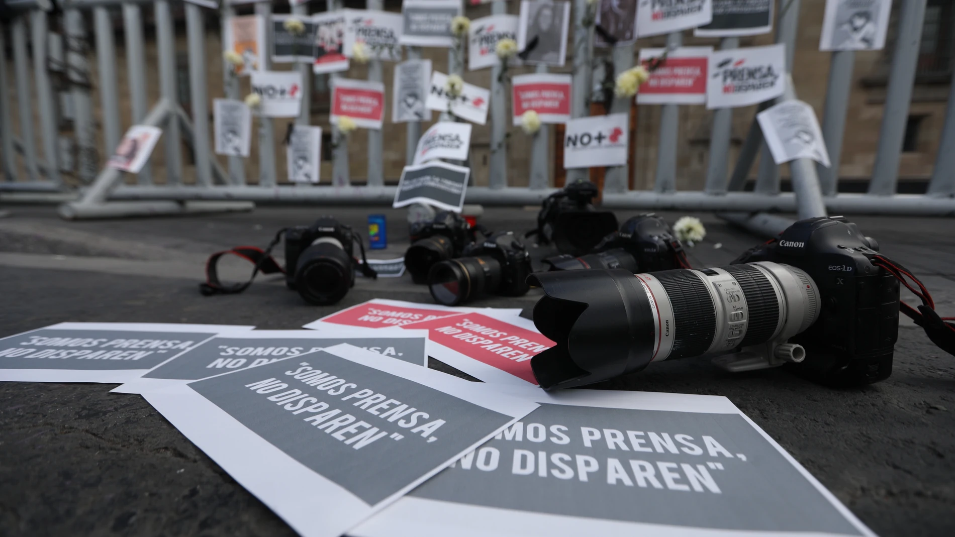 Foto de Archivo: Fotografía de carteles, flores, retratos y cámaras fotográficas en el suelo como acto de protesta por los asesinatos a periodistas