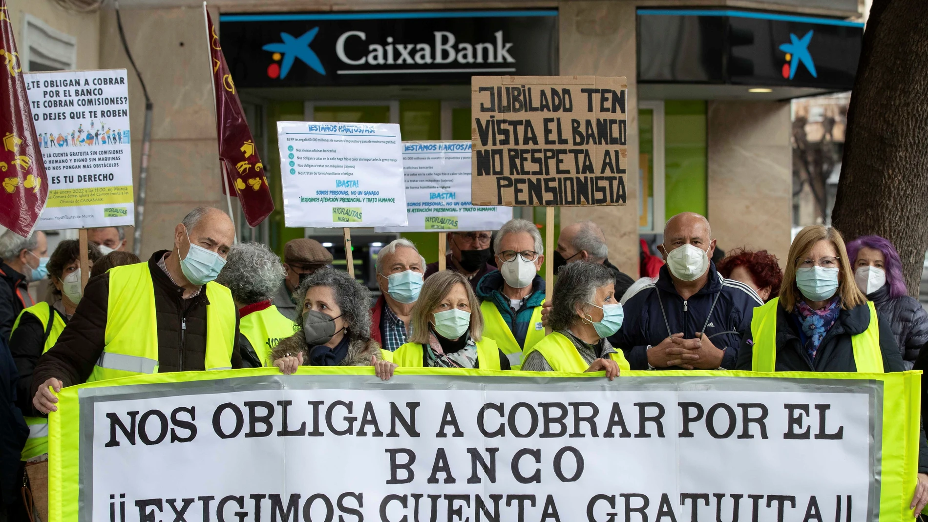 Varios miembros de los colectivos Yayoflautas y Coespe-RM se manifiestan este martes ante una sucursal bancaria del barrio del Carmen de Murcia, para exigir la cuenta gratuita sin comisiones o cuenta básica, así como un "trato humano y digno sin máquinas"