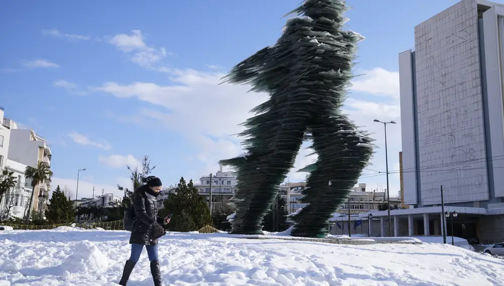 Una mujer camina delante de una escultura congelada de Kostas Varotsos