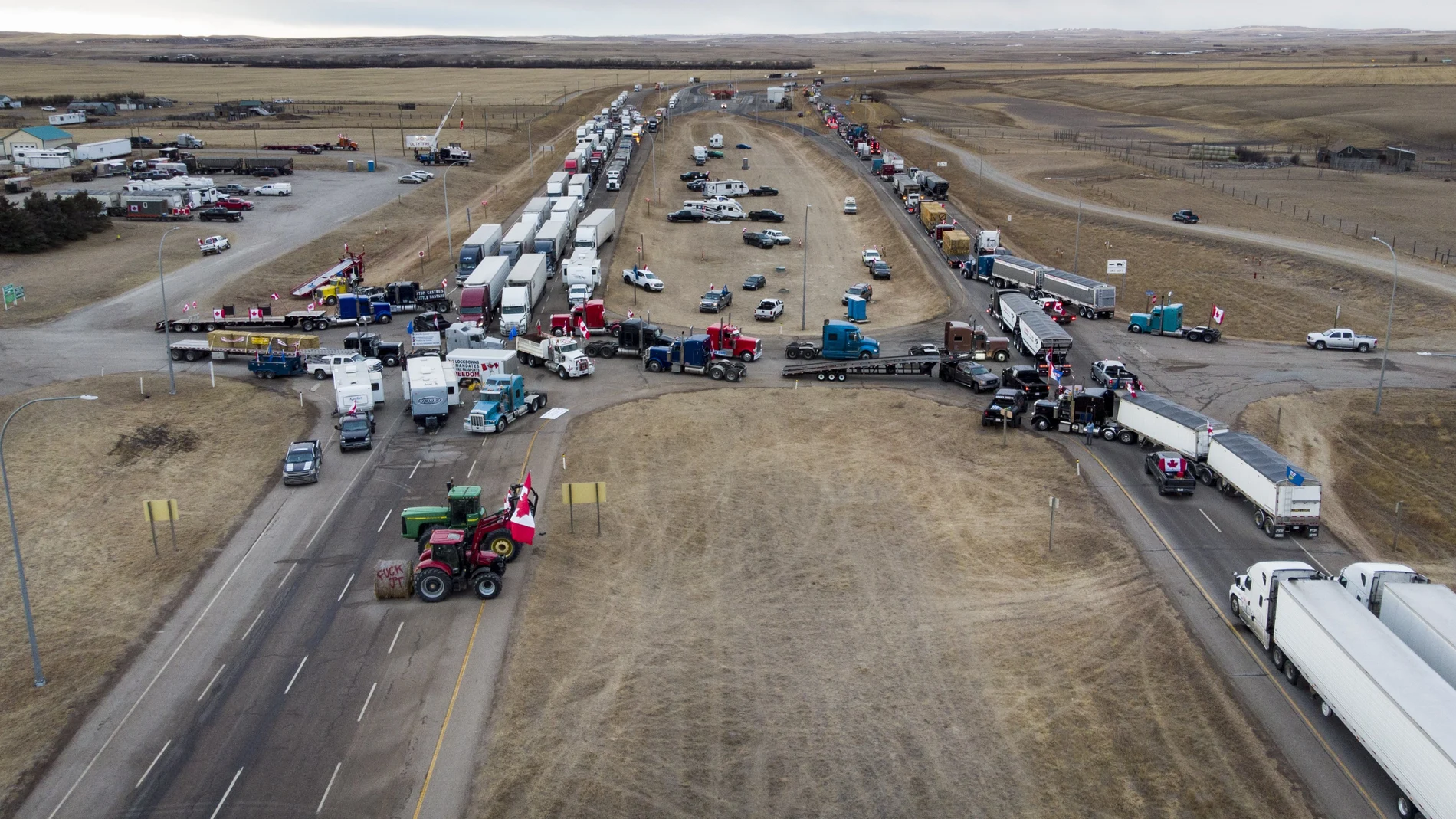 Anti-COVID-19 vaccine mandate demonstrators gather as a truck convoy blocks the highway at the busy U.S. border crossing in Coutts, Alberta, Canada, Monday, Jan. 31, 2022. (Jeff McIntosh/The Canadian Press via AP)