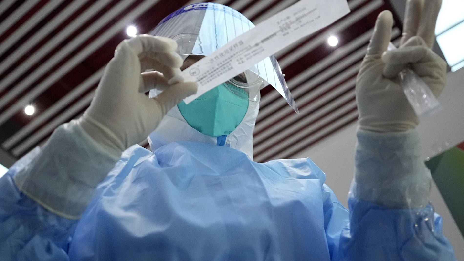 Un sanitario se prepara para tomar una muestra de hisopo para una prueba de COVID-19 en el Aeropuerto Internacional de la Capital de Beijing antes de los Juegos Olímpicos de Invierno de 2022