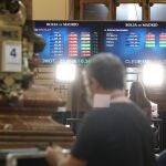 Un hombre delante de dos paneles con valores del Ibex 35, en el Palacio de la Bolsa, a 4 de febrero de 2022