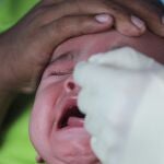 Un bebé de seis meses, reacciona mientras un sanitario toma una muestra para el test covid en Malasia