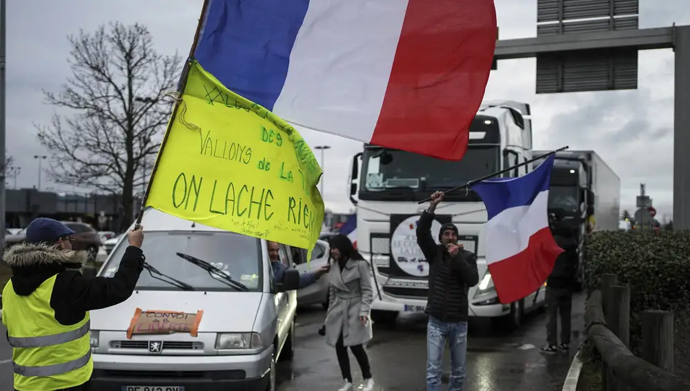 Un manifestante ondea una bandera francesa frente a un convoy compuesto por vehículos, desde camiones hasta motocicletas y autocaravanas en Lyon, centro de Francia