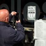 Un hombre toma una fotografía de un cartel en el centro de vacunación del WiZink Center de Madrid, donde desde hoy no es necesaria la cita previa