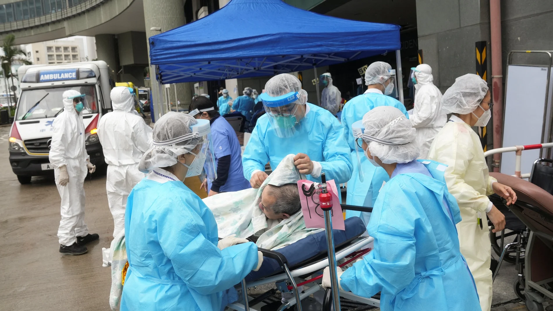 Sanitarios mueven a un paciente en un área de tratamiento improvisada fuera de un hospital