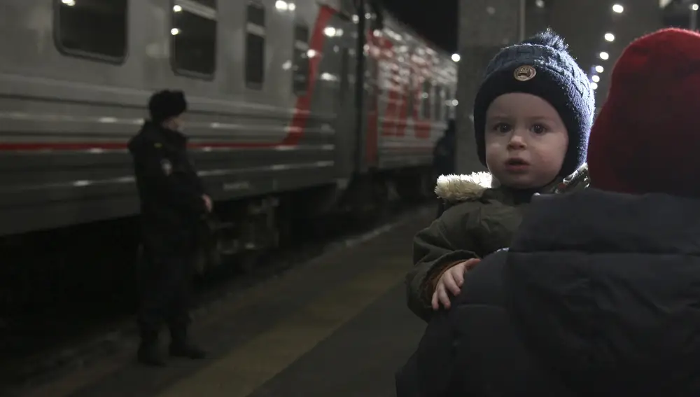 Una mujer lleva a un niño con otras personas que evacuaron de la región de Donetsk, el territorio controlado por los gobiernos separatistas prorrusos en el este de Ucrania, mientras salen de un tren para ser llevados a residencias temporales en la región de Nizhny Novgorod, en la estación de tren en Nizhny Novgorod, Rusia