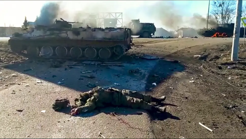 El cuerpo de un soldado ucraniano yace en el suelo junto a vehículos militares destrozados tras un ataque en el Este de Ucrania