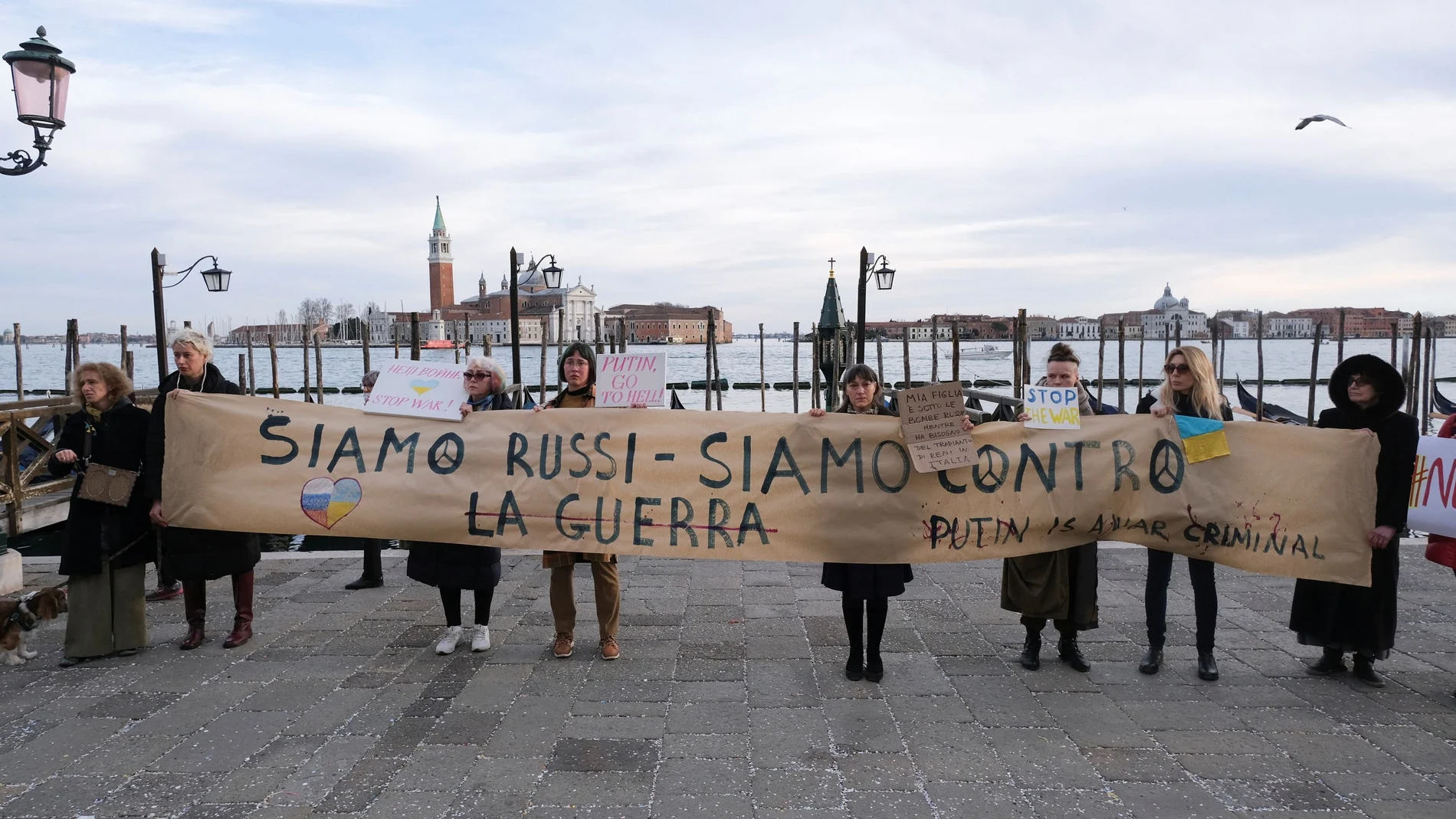 La gente sostiene una pancarta que dice "Somos rusos, estamos en contra de la guerra. Putin es un criminal de guerra" en Venecia.  REUTERS/Manuel Silvestri