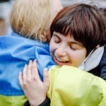 Dos personas se abrazan con una bandera de Ucrania durante una manifestación frente a la Embajada de Rusia en Madrid, a 25 de febrero de 2022 | Fuente: Carlos Luján / Europa Press